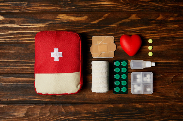 top view of first aid kit bag with medicines on wooden tabletop - Fotoğraf, Görsel