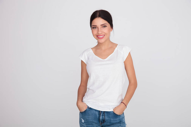 relaxed girl with casual clothes standing on light grey background with hands in pockets - Foto, immagini