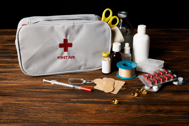 close-up shot of first aid kit with different medicines on wooden tabletop and on black - Foto, immagini