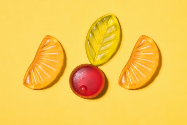 top view of tasty gummy fruits on yellow surface - Фото, зображення