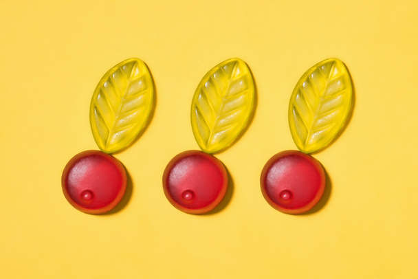 top view of gummy cherries on yellow surface - Fotoğraf, Görsel