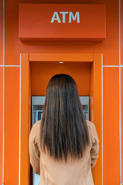 Обратная сторона женщины снятия наличных через банкомат, бизнес Автоматический кассир концепции
 - Фото, изображение