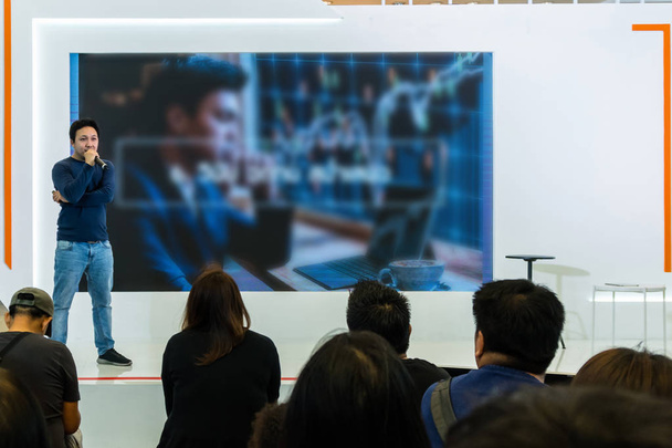 asiatischer Redner im lässigen Anzug auf der Bühne über der Präsentationsleinwand im Business- oder Bildungsseminar - Foto, Bild