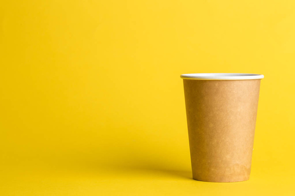 coffee to go in a disposable cup on a yellow background, place for text - Фото, изображение