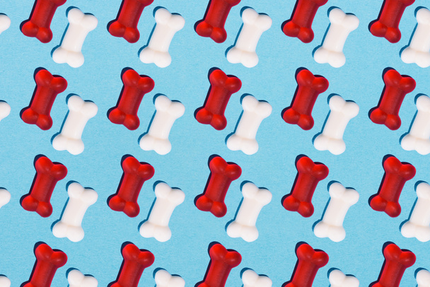top view of red and white gummy candies in shape of bones pattern on blue - Photo, Image