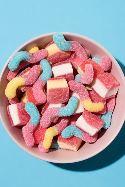 vista superior de coloridos caramelos de goma en tazón en azul
 - Foto, imagen