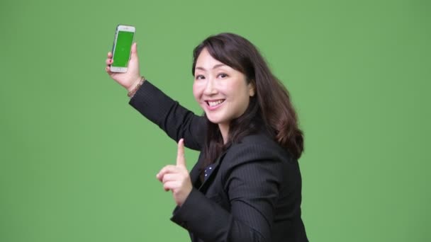 Mature happy Asian businesswoman video calling with phone - Video, Çekim
