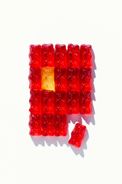 bovenaanzicht van rode gedefragmenteerde rechthoek van gummy beren op wit - Foto, afbeelding