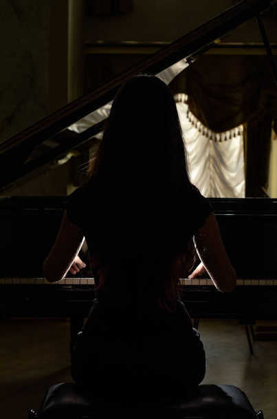 Young charming brunette girl playing the piano - Fotó, kép