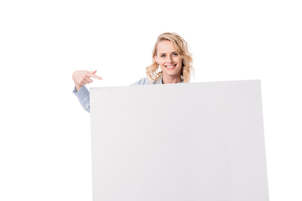 smiling attractive woman pointing on empty board isolated on white - Foto, imagen
