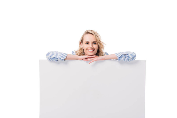 smiling attractive woman leaning on blank placard isolated on white - Foto, afbeelding