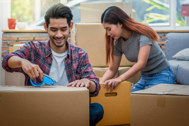 Asian young couple packing the big cardboard box for moving in new house, Moving and House Hunting concept, - Photo, Image
