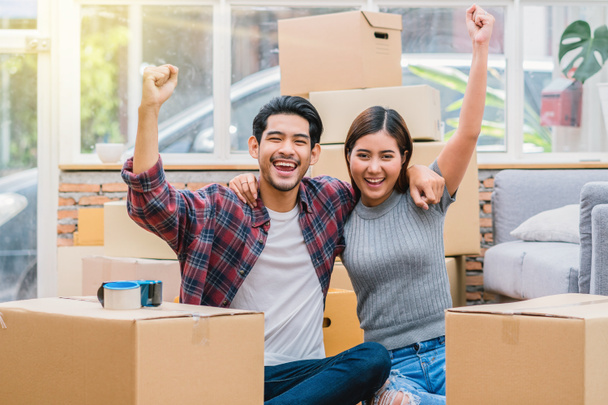 Asian young couple are glad after successfull packing the big cardboard box for moving in new house, Moving and House Hunting concept, - Photo, Image