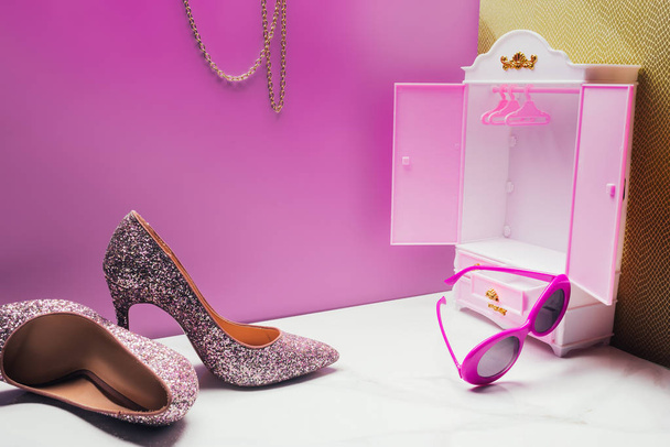 toy wardrobe with real size high heels and vintage sunglasses in miniature pink room - Photo, Image