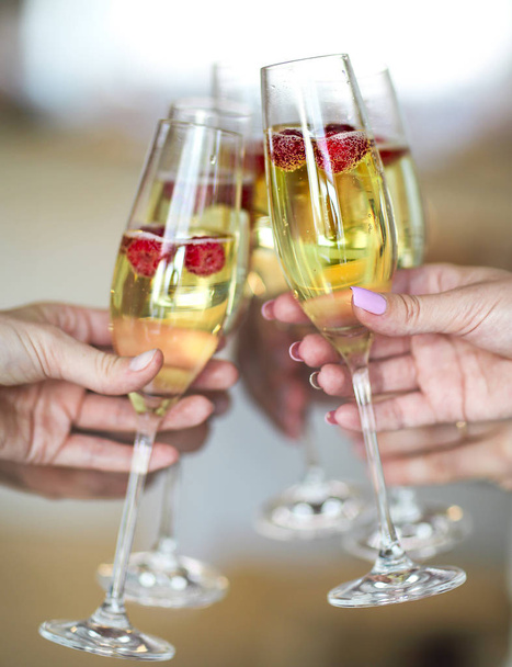 As pessoas seguram copos de champanhe com framboesa. Festa do vinho de verão
 - Foto, Imagem