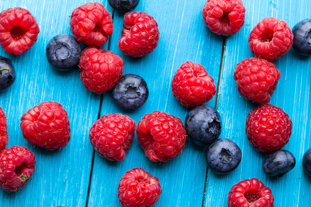 Blueberries and raspberries bowl on wooden table - Valokuva, kuva