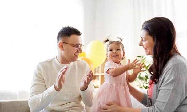 happy baby girl and parents at home birthday party - Photo, Image