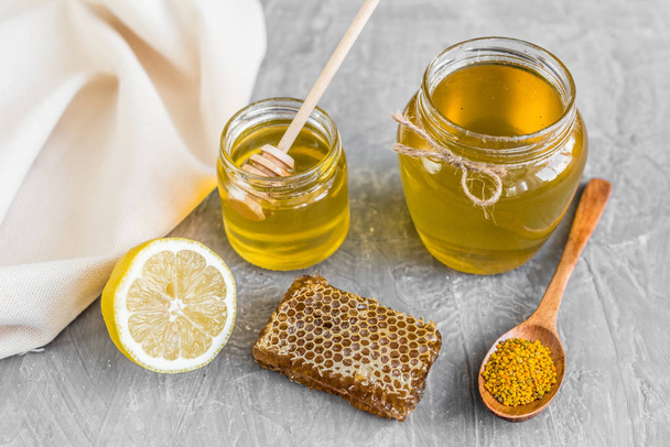 Beautiful transparent honey in bank, honeycombs and pollen on a wooden table. It can be used as a background - Fotografie, Obrázek