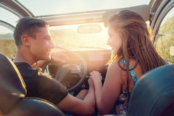 Happy young couple in a car enjoying the beautiful sunset in countryside. - 写真・画像