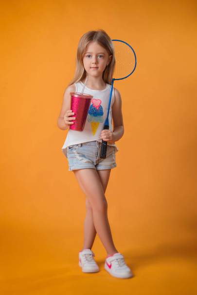 Kis lány pózol egy teniszütőt és egy shaker a stúdióban - Fotó, kép