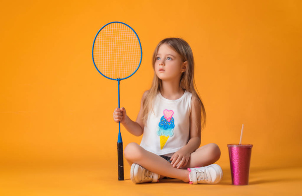 Маленька дівчинка позує з тенісною ракеткою і шейкером в студії
 - Фото, зображення