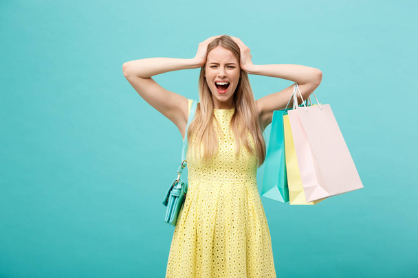 ショッピングと販売コンセプト:美しい不幸な若い女性で黄色エレガントなドレスでショッピングバッグ. - 写真・画像