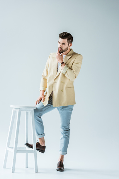 Handsome bearded man leaning on stool on white background - Fotografie, Obrázek