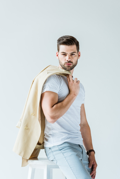 Fashionable confident man holding his jacket isolated on white background - 写真・画像