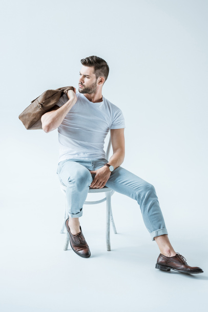 Fashionable confident man sitting on chair and holding briefcase on white background - Fotoğraf, Görsel