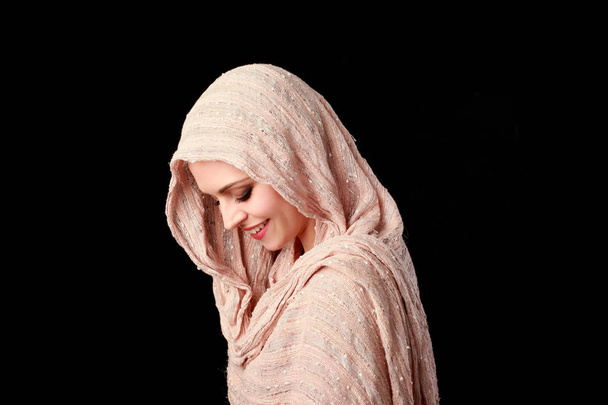 Porträt eines hübschen Mädchens mit rosa Kopftuch. schwarzer Studiohintergrund. - Foto, Bild