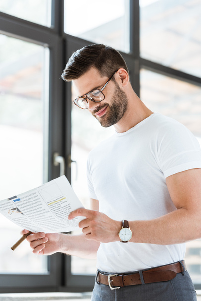 Fashionable confident businessman in glasses smiling while reading business report - Photo, Image