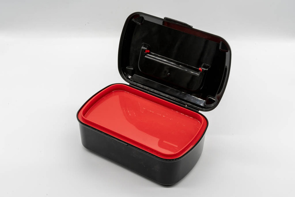 Чорно-червона пластикова коробка ізольована на білому тлі
 - Фото, зображення