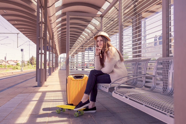 Portret van een tienermeisje met een koffer op het station - Foto, afbeelding