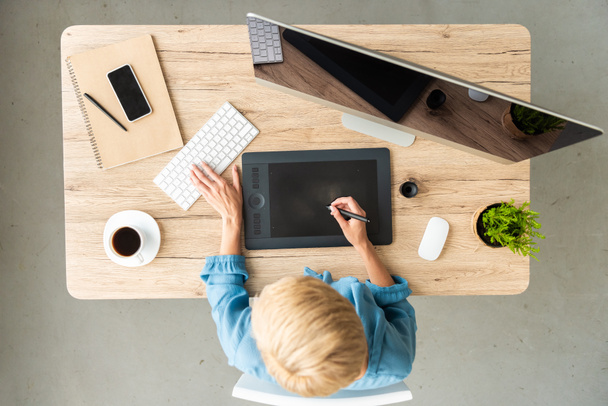 вид сверху женщины-фрилансера, работающей на графическом планшете за столом с чашкой кофе, смартфоном и компьютером в домашнем офисе
  - Фото, изображение