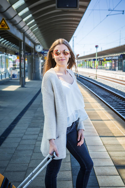πορτρέτο ενός έφηβου κοριτσιού με μια βαλίτσα στο σιδηροδρομικό σταθμό - Φωτογραφία, εικόνα