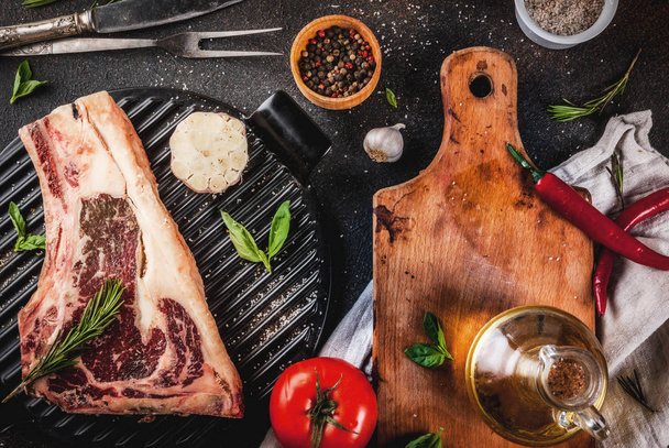 Márványos nyers marha hús striplon rib eye steak grill pan, fűszerek és gyógynövények, sötét háttér felülnézet, másol hely - Fotó, kép