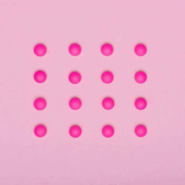 Kirkas vaaleanpunainen pillereitä peräkkäin, eristetty vaaleanpunainen pastelli värillinen tausta. Lääkitys ja reseptiä pillereitä tasainen lay tausta
. - Valokuva, kuva