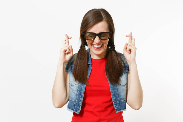 Ritratto di giovane bella donna felice in occhiali 3d e vestiti casual guardando film, tenendo le dita incrociate e gli occhi chiusi isolati in studio su sfondo bianco. Emozioni nel concetto di cinema
 - Foto, immagini