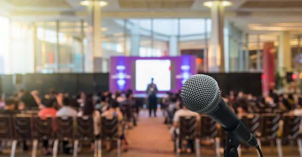 Microphone over the Abstract blurred photo of conference hall or seminar room with Speakers on the stage and attendee background, Business meeting concept - Photo, Image
