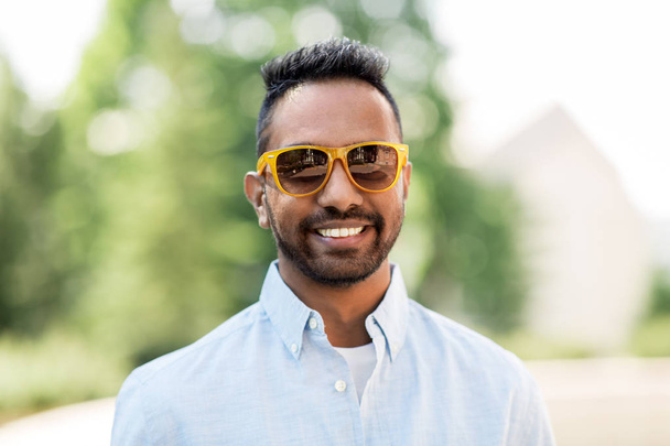 happy young indian man in sunglasses outdoors - Фото, изображение