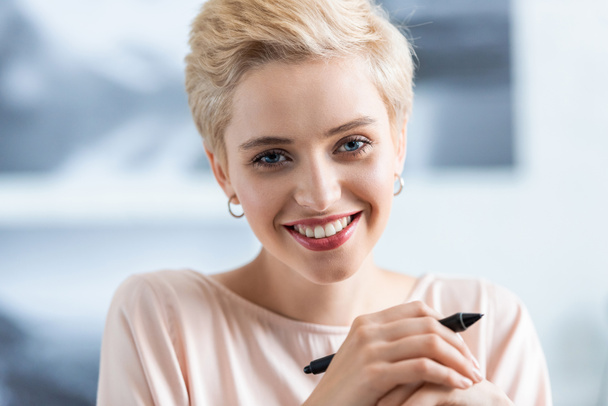 Close-up van portret van lachende aantrekkelijke vrouw met pen voor grafisch tablet  - Foto, afbeelding