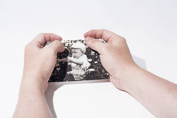 Old paper photo in mans hands. Abstract photo of childhood. - Photo, Image