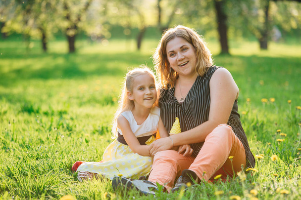 Mother and daughter having fun in the park. Happiness and harmony in family life.  Beauty nature scene with family outdoor lifestyle.  - Foto, afbeelding
