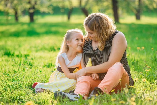 Anya és lánya jól érzik magukat a parkban. Boldogság és harmónia a családi életben. Szépség természet jelenet családi szabadtéri életmód.  - Fotó, kép