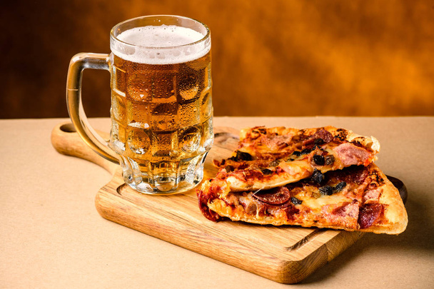 Slice of delicious homemade pizza served with light cold beer on - Foto, imagen