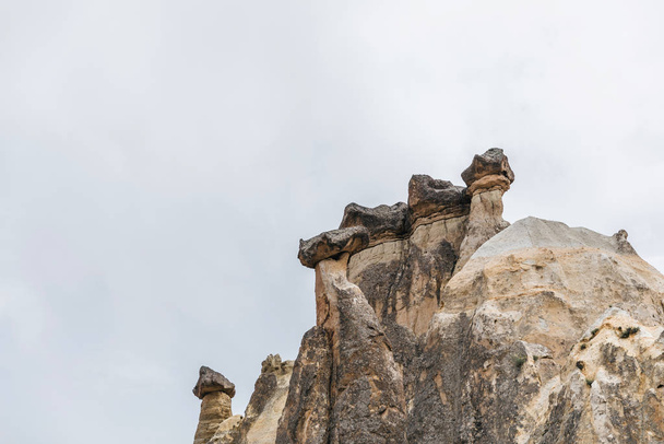 beautiful rock formations against cloudy sky in cappadocia, turkey - Photo, Image