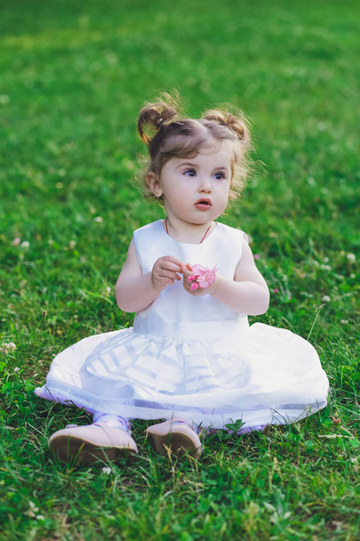 Ребенок, маленькая девочка в платье в парке на траве
 - Фото, изображение