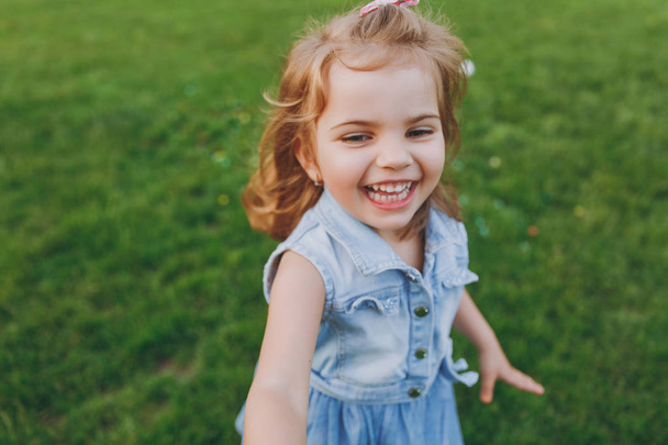 Joyful pequena menina bebê bonito em vestido de ganga andando e correndo, divirta-se no gramado de grama verde no parque. Mãe, filhinha. Dia das Mães, família do amor, paternidade, conceito de infância
 - Foto, Imagem
