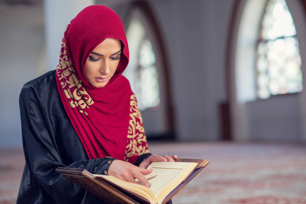 Мусульманка, читающая Коран или Коран в традиционном платье в мечети - Фото, изображение