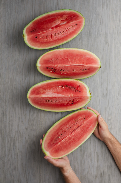 partial view of male hands and fresh watermelon slices on grey wooden tabletop - Foto, immagini